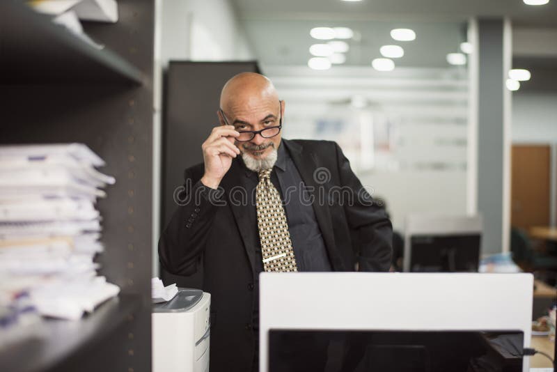 Hombre calvo mayor que trabaja en oficina con el traje negro imagen de archivo libre de regalías Hombre calvo mayor que trabaja en oficina con el traje negro imagen de archivo libre de regalías
