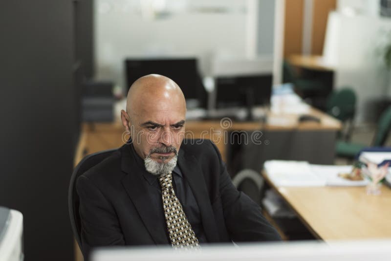 Hombre calvo mayor que trabaja en oficina con el traje negro foto de archivo Hombre calvo mayor que trabaja en oficina con el traje negro foto de archivo