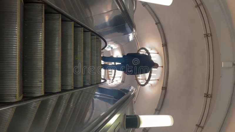 Hombre caminando en escaleras mecánicas en un edificio iluminado