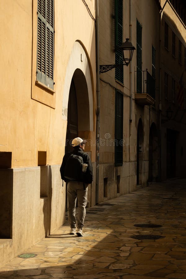 Hombre caminando por una callejuela en el centro de Palma de Mallorca iluminado por el sol foto de archivo libre de regalías