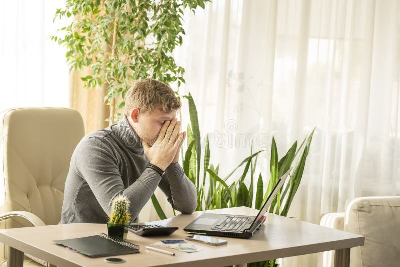 tired young man working on laptop at workplace. tired young man working on laptop at workplace