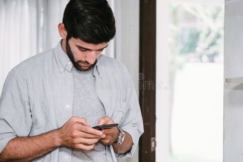 Hombre caucásico con bigote y barba escribiendo en su teléfono móvil fotografía de archivo libre de regalías