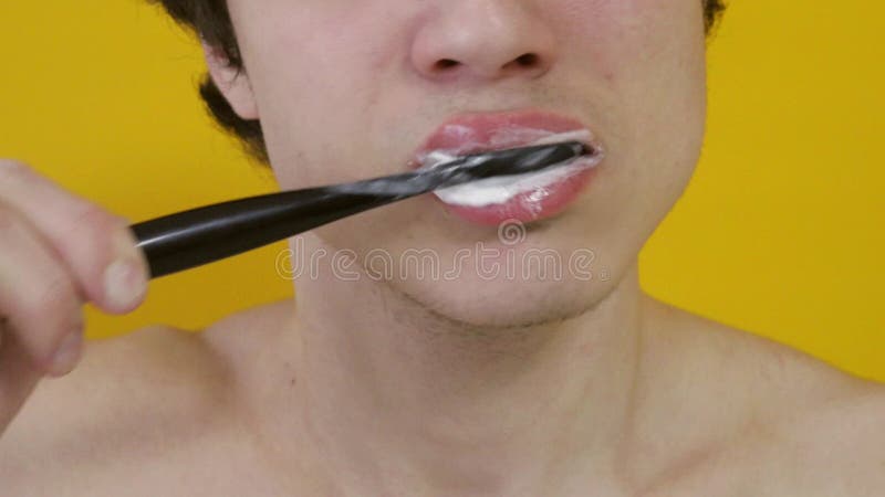 Hombre cepillando dientes en fondo amarillo
