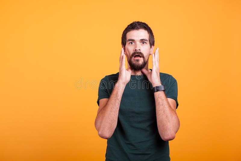 Hombre chocado con las manos en su cara que mira la cámara imagen de archivo libre de regalías Hombre chocado con las manos en su cara que mira la cámara imagen de archivo libre de regalías