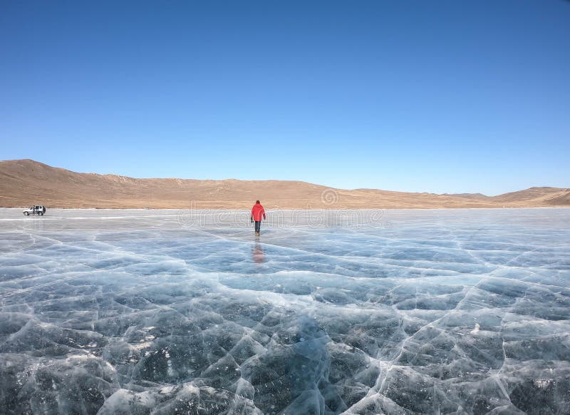Hombre con abrigo rojo de invierno camina en el lago Baikal congelado en invierno fotos de archivo libres de regalías Hombre con abrigo rojo de invierno camina en el lago Baikal congelado en invierno fotos de archivo libres de regalías