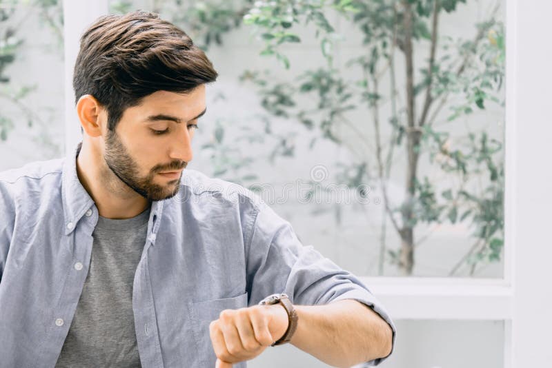Hombre con barba y bigote mirando el reloj de la mano fotografía de archivo libre de regalías