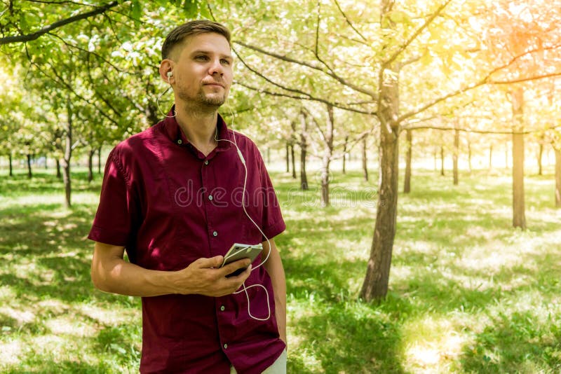 Hombre con el teléfono móvil en parque del verano Hombre hermoso joven con el SM fotografía de archivo libre de regalías Hombre con el teléfono móvil en parque del verano Hombre hermoso joven con el SM fotografía de archivo libre de regalías