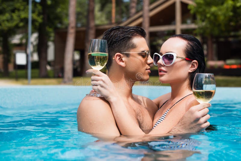 Hombre Con Gafas De Sol Sosteniendo Un Cóctel Cerca De Una Novia Morena En  La Piscina Fotos, retratos, imágenes y fotografía de archivo libres de  derecho. Image 172222376