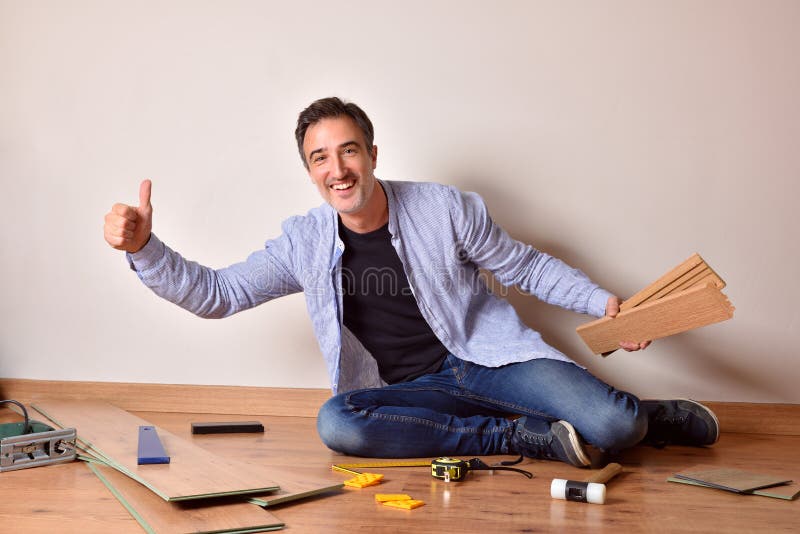 Hombre con gesto ok poniendo parquet en su propia casa imágenes de archivo libres de regalías