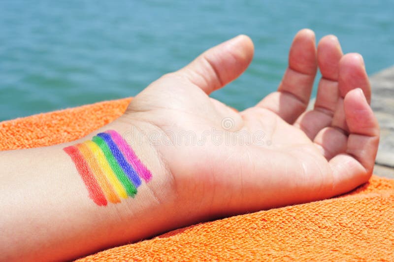 Hombre con la bandera del arco iris pintada en su muñeca foto de archivo libre de regalías Hombre con la bandera del arco iris pintada en su muñeca foto de archivo libre de regalías