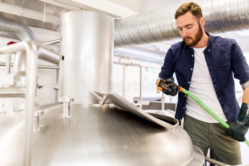 Hombre con la manguera que trabaja en la caldera de la cervecería de la cerveza del arte imagen de archivo Hombre con la manguera que trabaja en la caldera de la cervecería de la cerveza del arte imagen de archivo