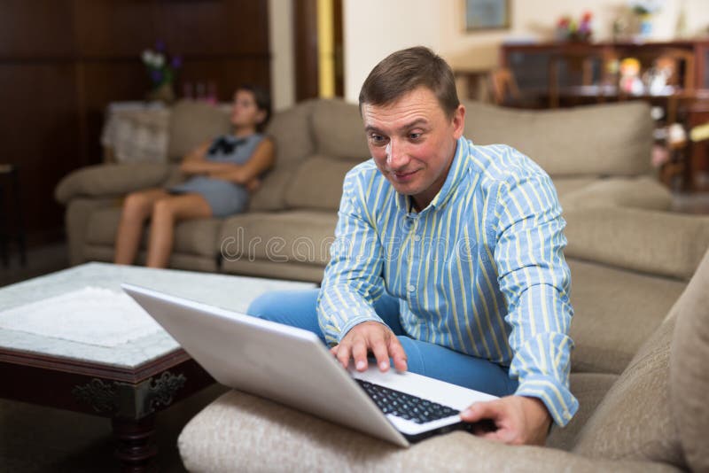 Hombre con laptop que ignora a su disgustada esposa