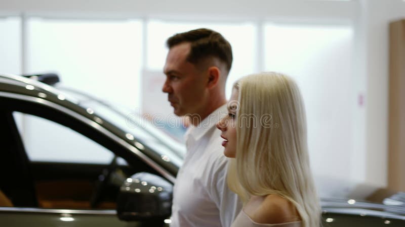 Hombre con una mujer rubia sexy vino a elegir el coche en el concesionario almacen de metraje de vídeo