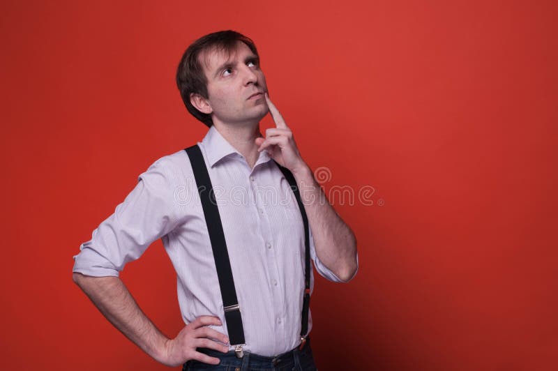 hombre confiado con la mano en cadera y el finger en mejilla en camisa rosada y la liga negra que miran lejos y que piensan foto de archivo hombre confiado con la mano en cadera y el finger en mejilla en camisa rosada y la liga negra que miran lejos y que piensan foto de archivo