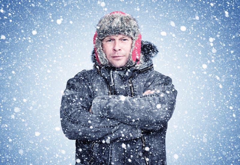 Hombre congelado con un abrigo de piel de oveja y que caliente sus manos, frío, nieve, helado, blizzard foto de archivo Hombre congelado con un abrigo de piel de oveja y que caliente sus manos, frío, nieve, helado, blizzard foto de archivo