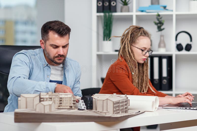 Hombre creativo trabajador cualificado y diseñadores de mujeres que trabajan con la maqueta de edificios y modelos en el ordenador foto de archivo libre de regalías