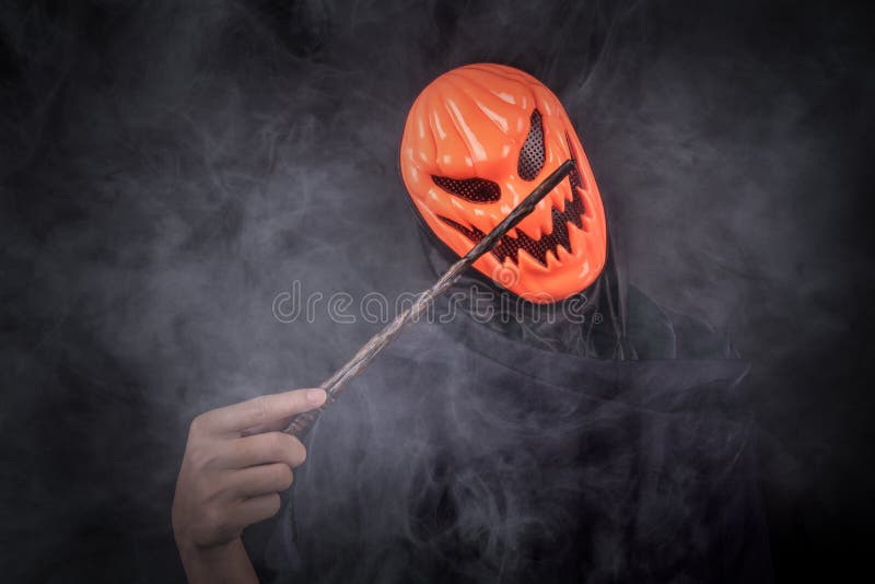 Hombre de Halloween con la máscara de la calabaza que sostiene la vara mágica foto de archivo Hombre de Halloween con la máscara de la calabaza que sostiene la vara mágica foto de archivo