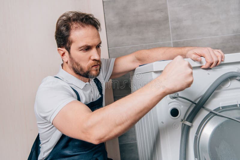 Hombre de mano seguro reparando lavadora imagenes de archivo