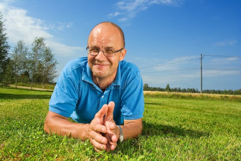 Hombre de mediana edad que sonríe en una hierba foto de archivo Hombre de mediana edad que sonríe en una hierba foto de archivo
