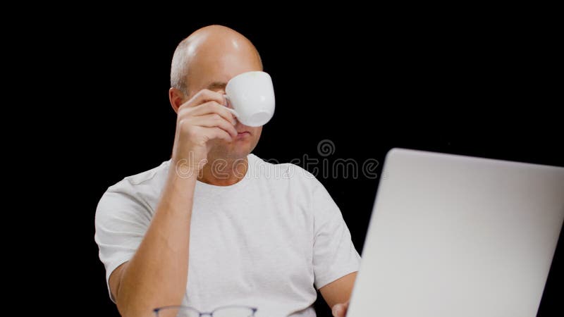 Hombre de mediana edad que usa laptop y bebe café delicioso