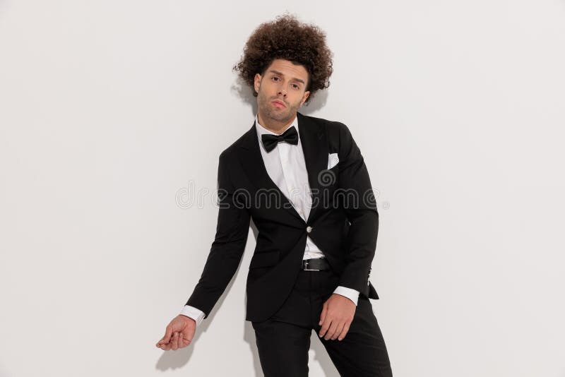 Hombre de moda genial con esmoquin negro posando de manera segura foto de archivo libre de regalías