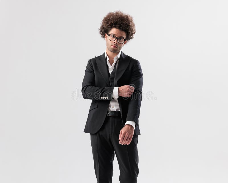 Hombre de moda sexy con pelo rizado y gafas ajustando la manga fotografía de archivo