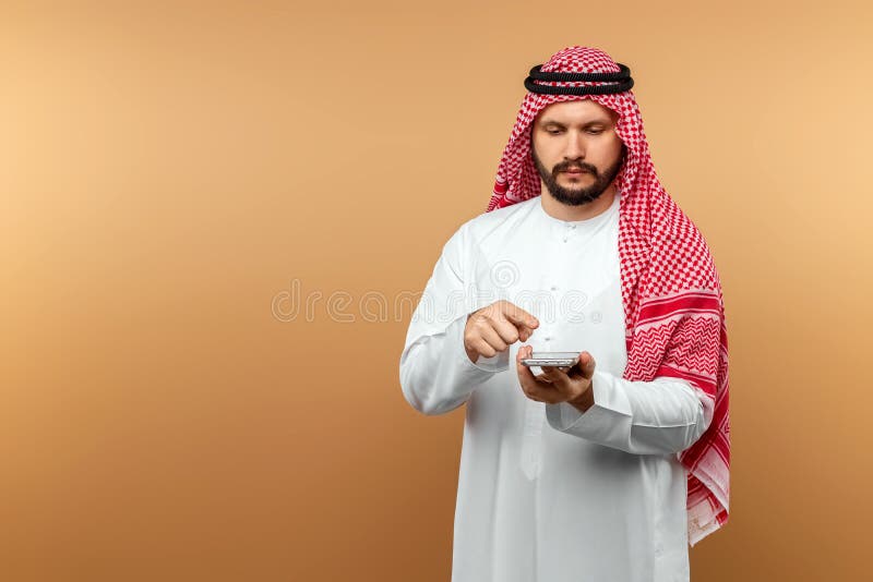 Hombre De Negocios árabe Vestido Traje Nacional Sostiene Teléfono Inteligente En Sus Manos Fondo Beige. Dishdasha Kandora Tú Foto de archivo - Imagen de sonrisa, adulto: 217026060