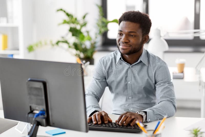 Hombre de negocios africano con el ordenador en la oficina foto de archivo