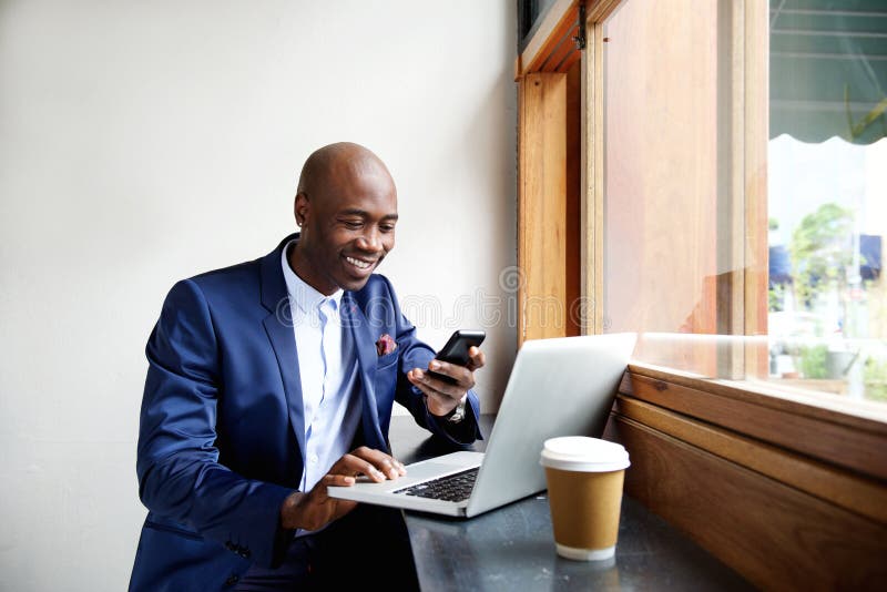 Hombre de negocios africano feliz usando el teléfono en el café imagen de archivo libre de regalías