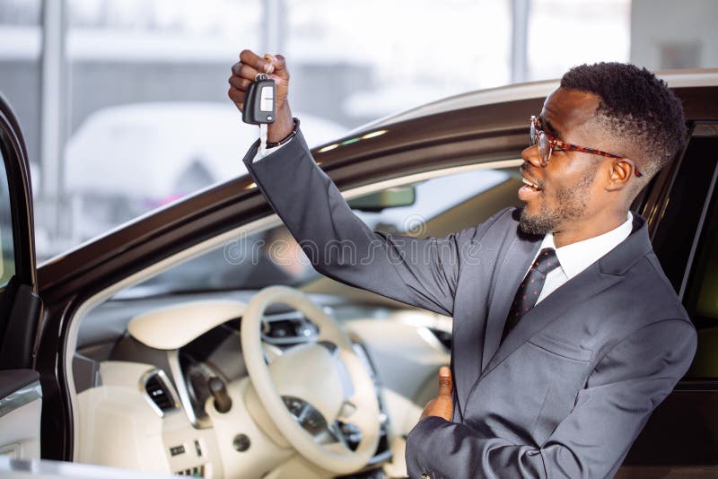 Hombre de negocios africano joven Sitting In un coche que muestra llave del coche foto de archivo Hombre de negocios africano joven Sitting In un coche que muestra llave del coche foto de archivo