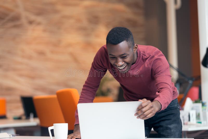 Hombre de negocios afroamericano acertado feliz en una oficina de lanzamiento moderna dentro foto de archivo libre de regalías Hombre de negocios afroamericano acertado feliz en una oficina de lanzamiento moderna dentro foto de archivo libre de regalías