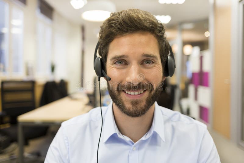 Hombre de negocios alegre en la oficina en videoconferencia, auriculares, foto de archivo libre de regalías Hombre de negocios alegre en la oficina en videoconferencia, auriculares, foto de archivo libre de regalías