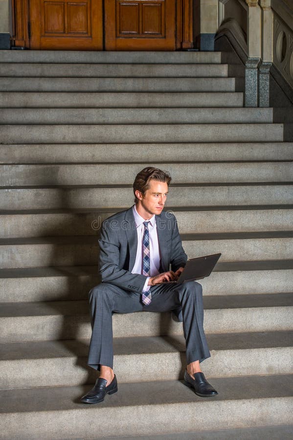 Hombre de negocios americano que trabaja en el ordenador portátil, sentándose en las escaleras fotografía de archivo Hombre de negocios americano que trabaja en el ordenador portátil, sentándose en las escaleras fotografía de archivo