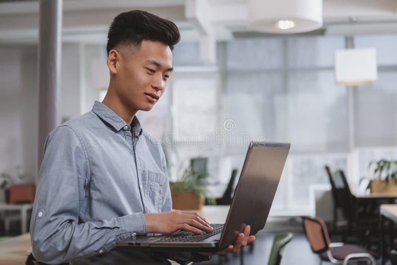 Hombre de negocios asi?tico joven que trabaja en la oficina imagen de archivo Hombre de negocios asi?tico joven que trabaja en la oficina imagen de archivo