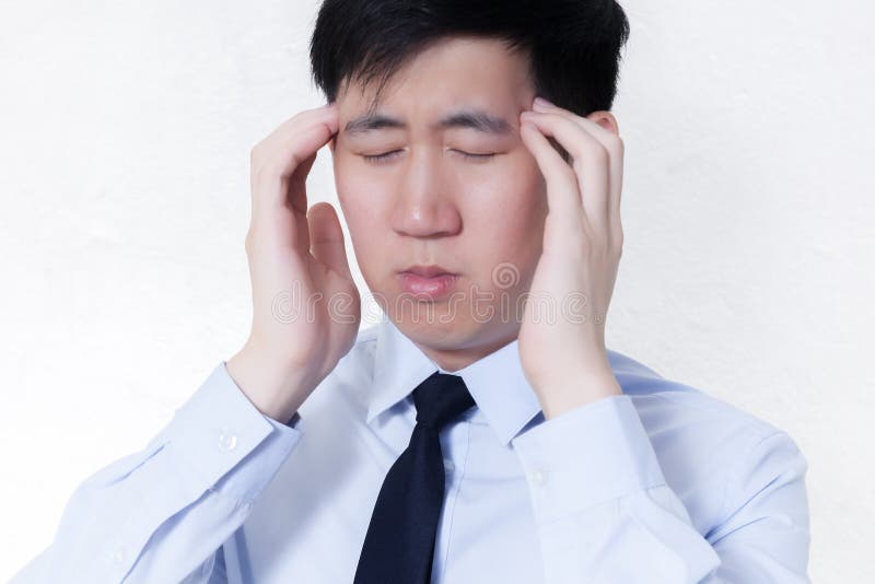 Hombre de negocios asiático joven que hace frente a problemas del dolor de cabeza/de la jaqueca en el blanco aislado imagen de archivo Hombre de negocios asiático joven que hace frente a problemas del dolor de cabeza/de la jaqueca en el blanco aislado imagen de archivo