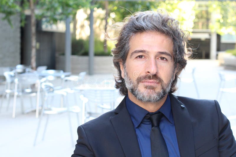 Hombre de negocios atractivo en el traje que se sienta fuera de su oficina fotos de archivo libres de regalías Hombre de negocios atractivo en el traje que se sienta fuera de su oficina fotos de archivo libres de regalías