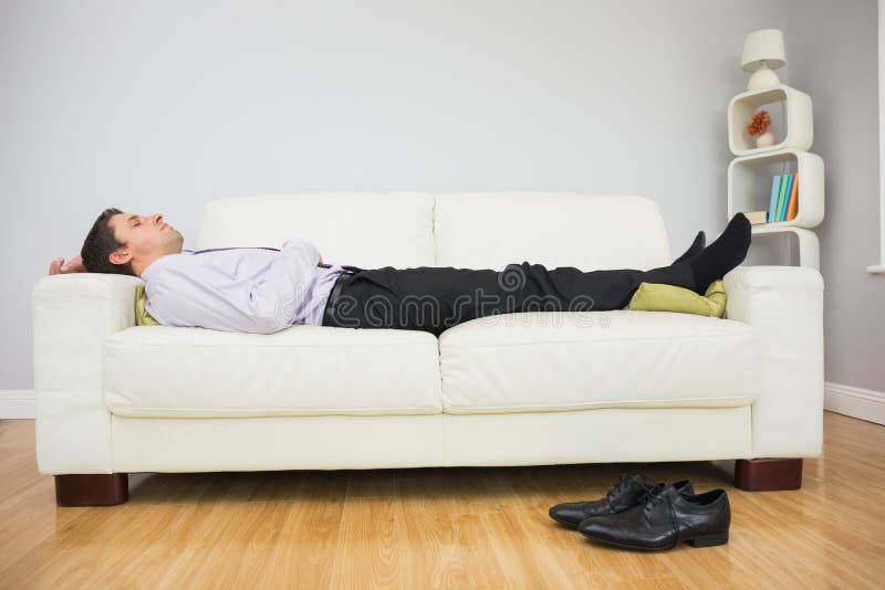 Hombre de negocios cansado que duerme en el sofá en sala de estar imágenes de archivo libres de regalías