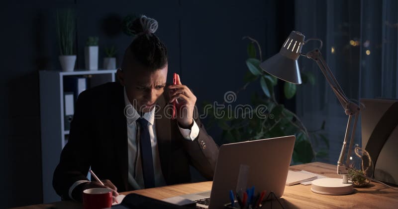 Hombre de negocios cansado que toma notas y que acaba el trabajo de oficina tarde en noche
