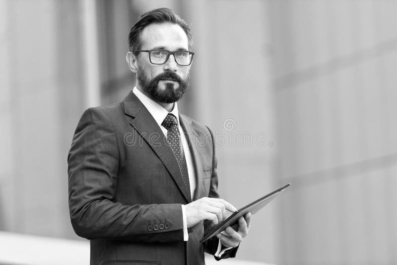 Hombre de negocios con la tableta a disposición en fondo del edificio de oficinas Hombre de negocios usando su tableta fuera de l fotografía de archivo libre de regalías Hombre de negocios con la tableta a disposición en fondo del edificio de oficinas Hombre de negocios usando su tableta fuera de l fotografía de archivo libre de regalías