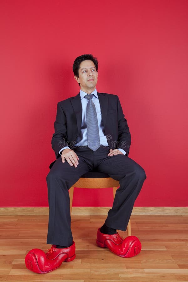 Hombre de negocios con los zapatos del payaso fotos de archivo Hombre de negocios con los zapatos del payaso fotos de archivo