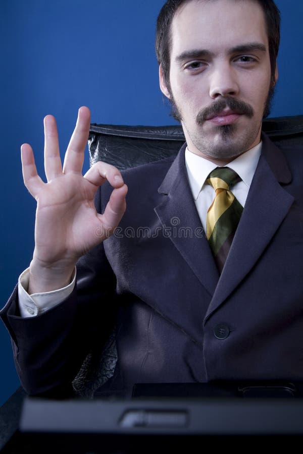 A portrait of a confident businessman sitting in a comfortable chair, giving the OK sign. A portrait of a confident businessman sitting in a comfortable chair, giving the OK sign.