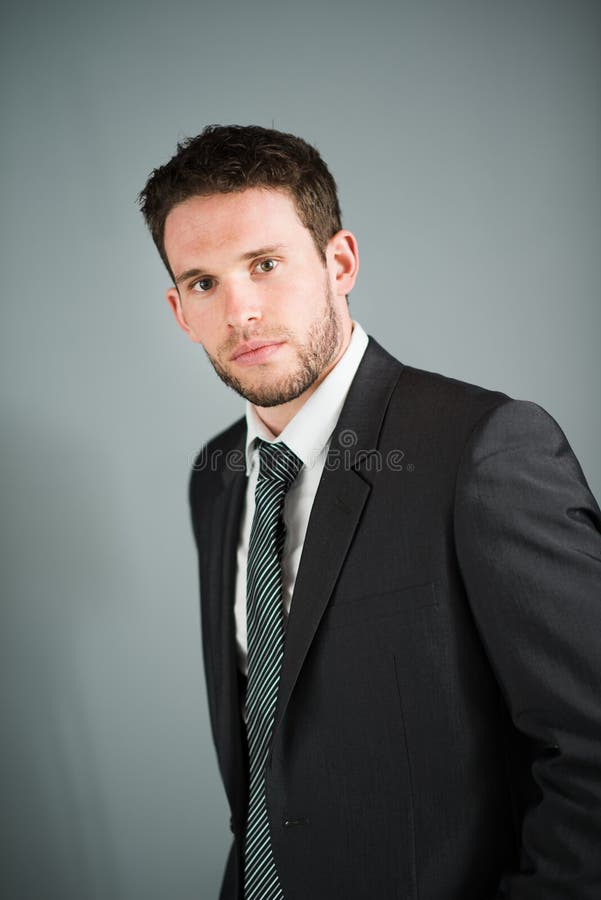 Hombre de negocios ejecutivo joven hermoso aislado en fondo gris foto de archivo Hombre de negocios ejecutivo joven hermoso aislado en fondo gris foto de archivo