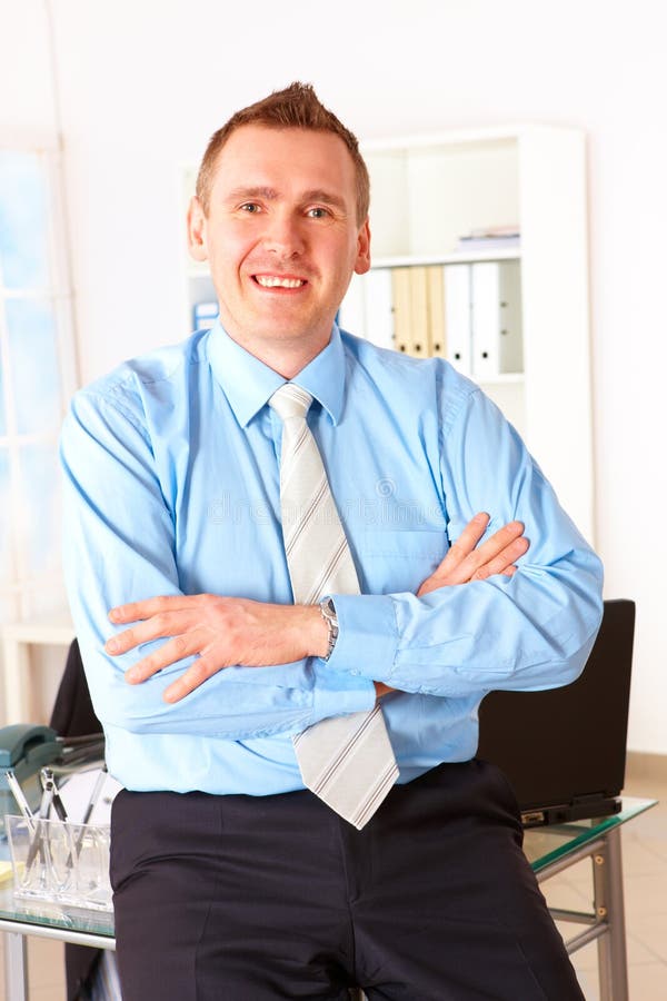 Hombre de negocios feliz que se inclina en el escritorio de oficina imagenes de archivo Hombre de negocios feliz que se inclina en el escritorio de oficina imagenes de archivo