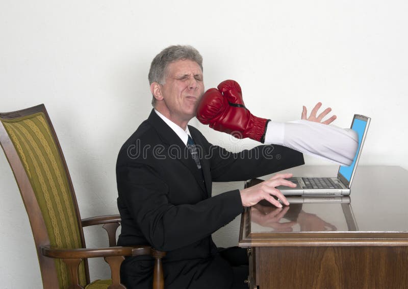 Must be a rough day on the internet! A businessman gets a surprise sucker punch as a fist with a boxing glove jumps out of his computer and hits him on the face and chin. Sometimes it doesn't pay to go to work and do your job!. Must be a rough day on the internet! A businessman gets a surprise sucker punch as a fist with a boxing glove jumps out of his computer and hits him on the face and chin. Sometimes it doesn't pay to go to work and do your job!