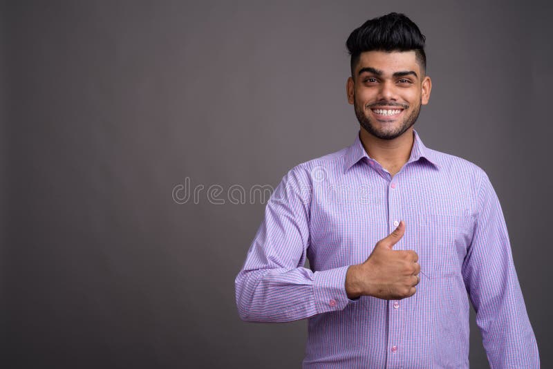 Hombre de negocios indio hermoso joven contra fondo gris foto de archivo libre de regalías Hombre de negocios indio hermoso joven contra fondo gris foto de archivo libre de regalías