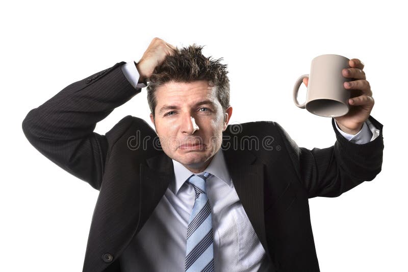 Hombre de negocios joven del adicto en traje y lazo que sostiene la taza de café vacía ansiosa imagen de archivo libre de regalías Hombre de negocios joven del adicto en traje y lazo que sostiene la taza de café vacía ansiosa imagen de archivo libre de regalías