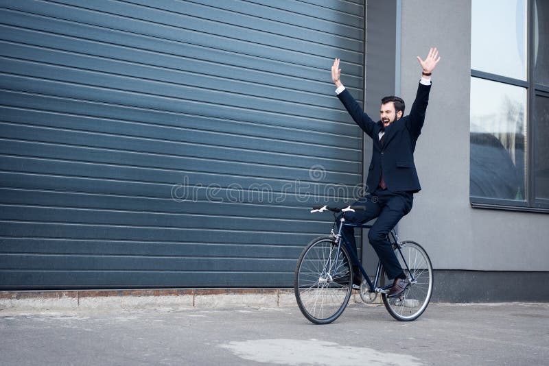 hombre de negocios joven emocionado con los brazos extendidos que montan la bicicleta fotos de archivo hombre de negocios joven emocionado con los brazos extendidos que montan la bicicleta fotos de archivo