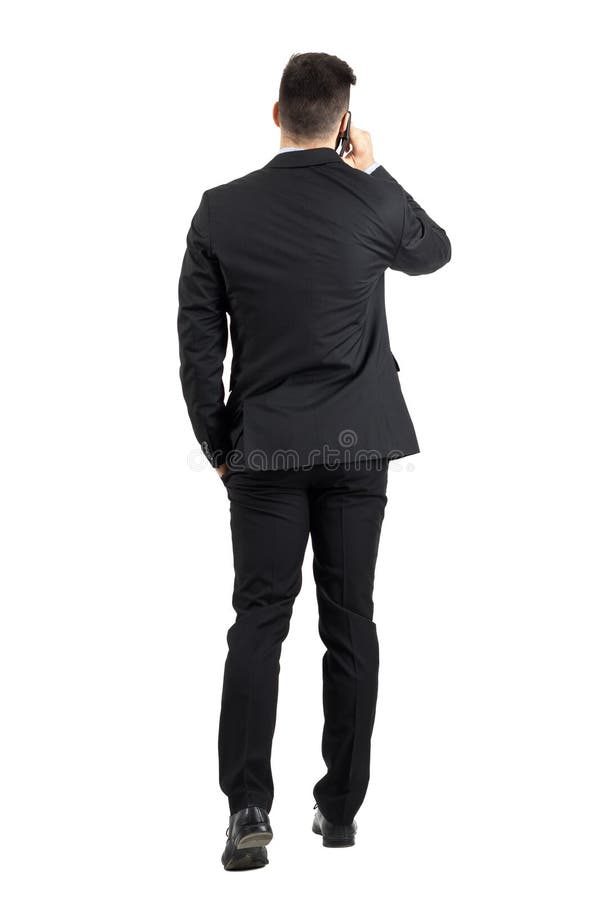 Hombre de negocios joven que habla en el teléfono que camina lejos vista posterior foto de archivo libre de regalías Hombre de negocios joven que habla en el teléfono que camina lejos vista posterior foto de archivo libre de regalías