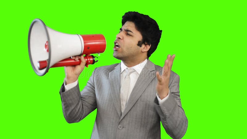 Hombre de negocios joven que habla en un megáfono en fondo verde