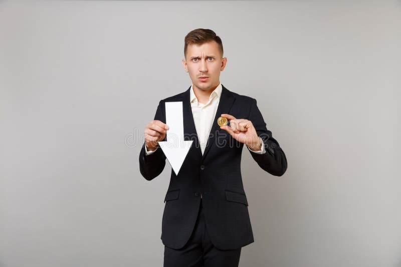 Hombre de negocios joven serio en la moneda futura del traje del mantenimiento del valor de la caída del bitcoin negro clásico de foto de archivo libre de regalías Hombre de negocios joven serio en la moneda futura del traje del mantenimiento del valor de la caída del bitcoin negro clásico de foto de archivo libre de regalías
